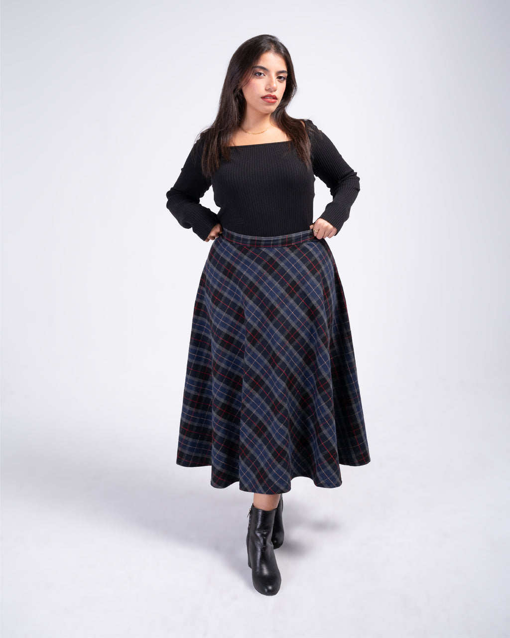 Woman wearing a black top and plaid skirt on a white background
