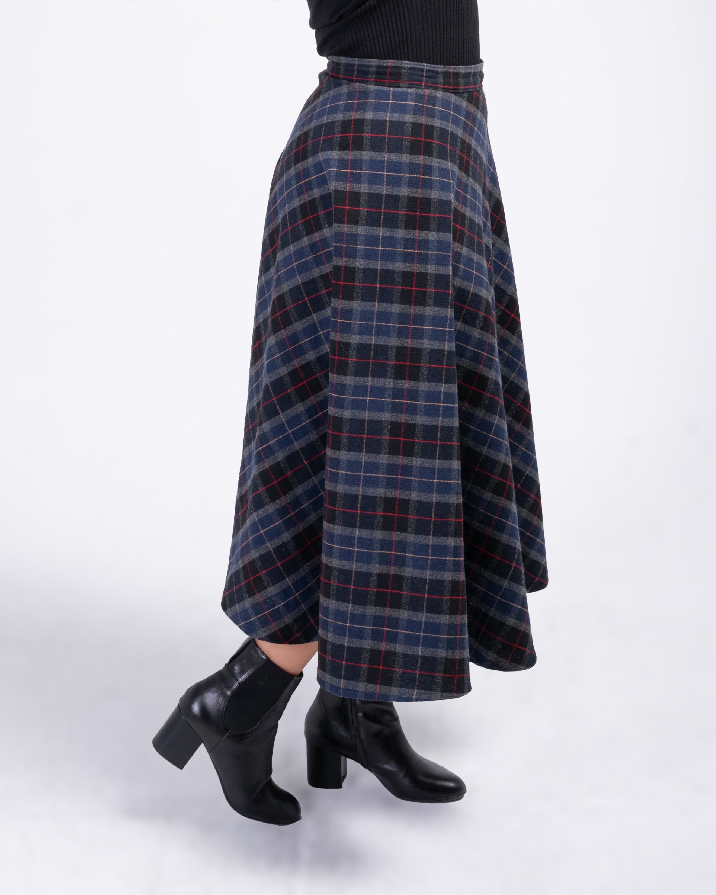 Person wearing a black top and plaid skirt on a white background