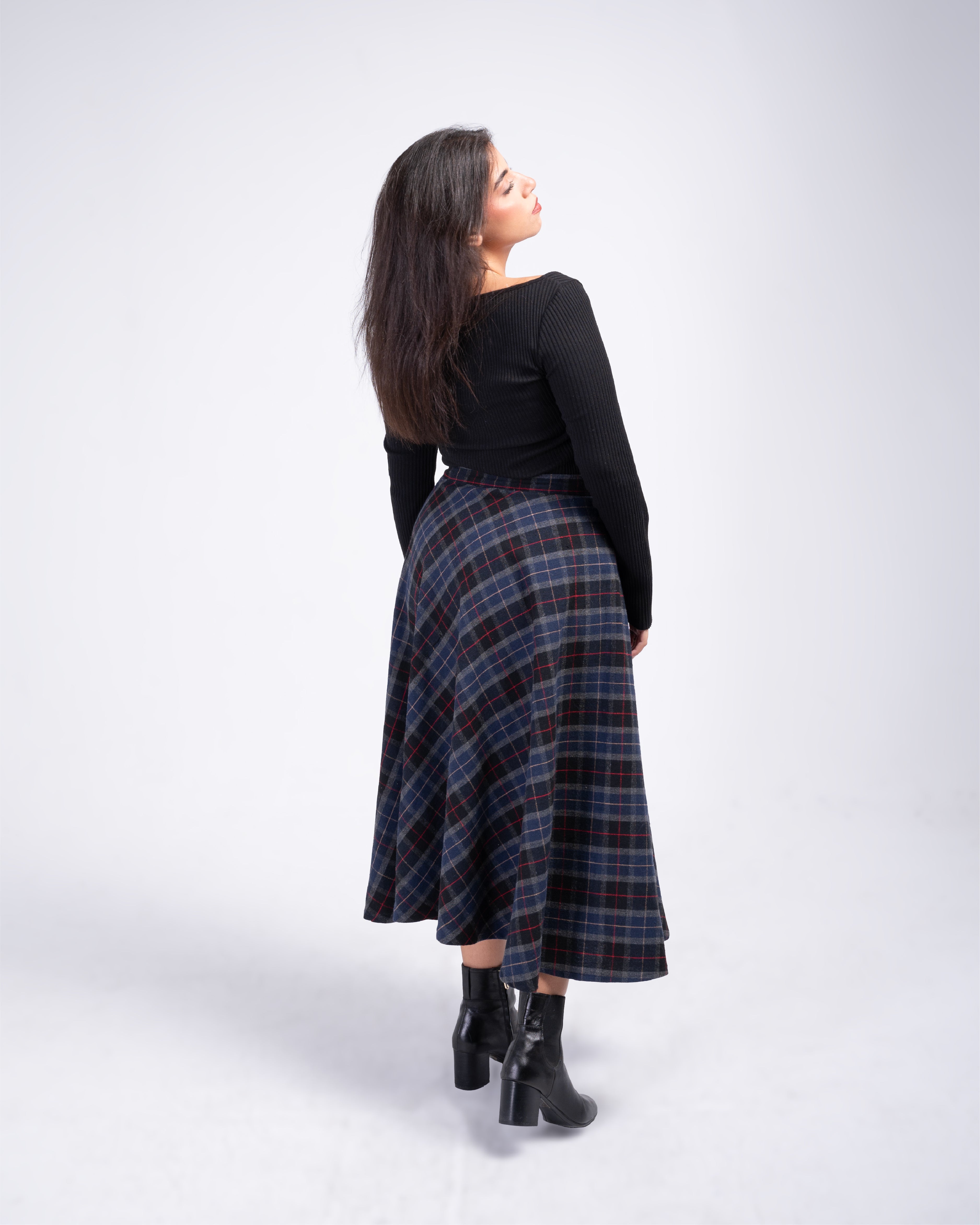 Woman wearing a black top and plaid skirt on a white background