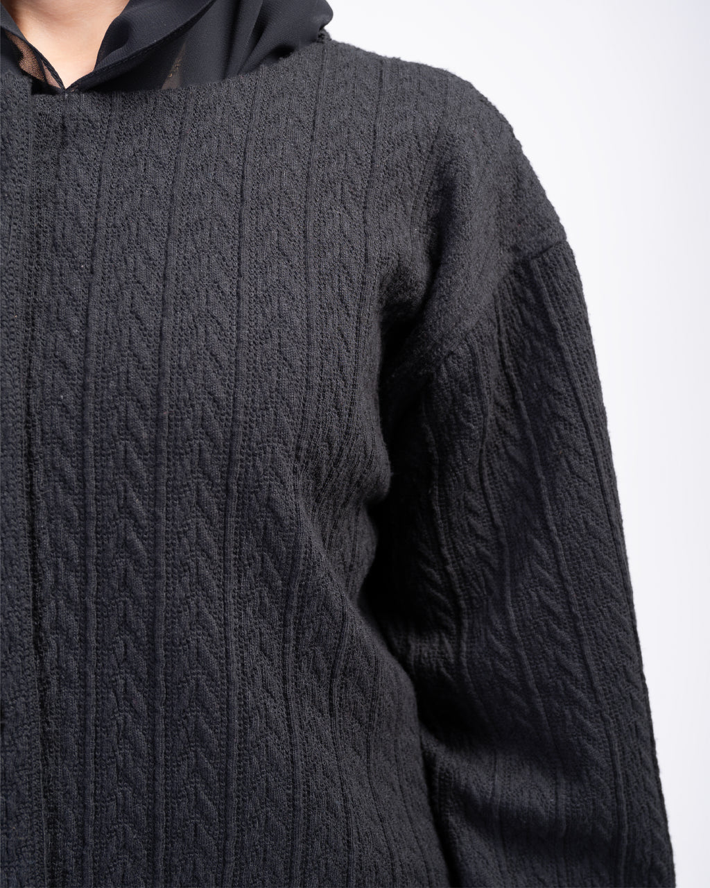 Black cable knit top on a white background