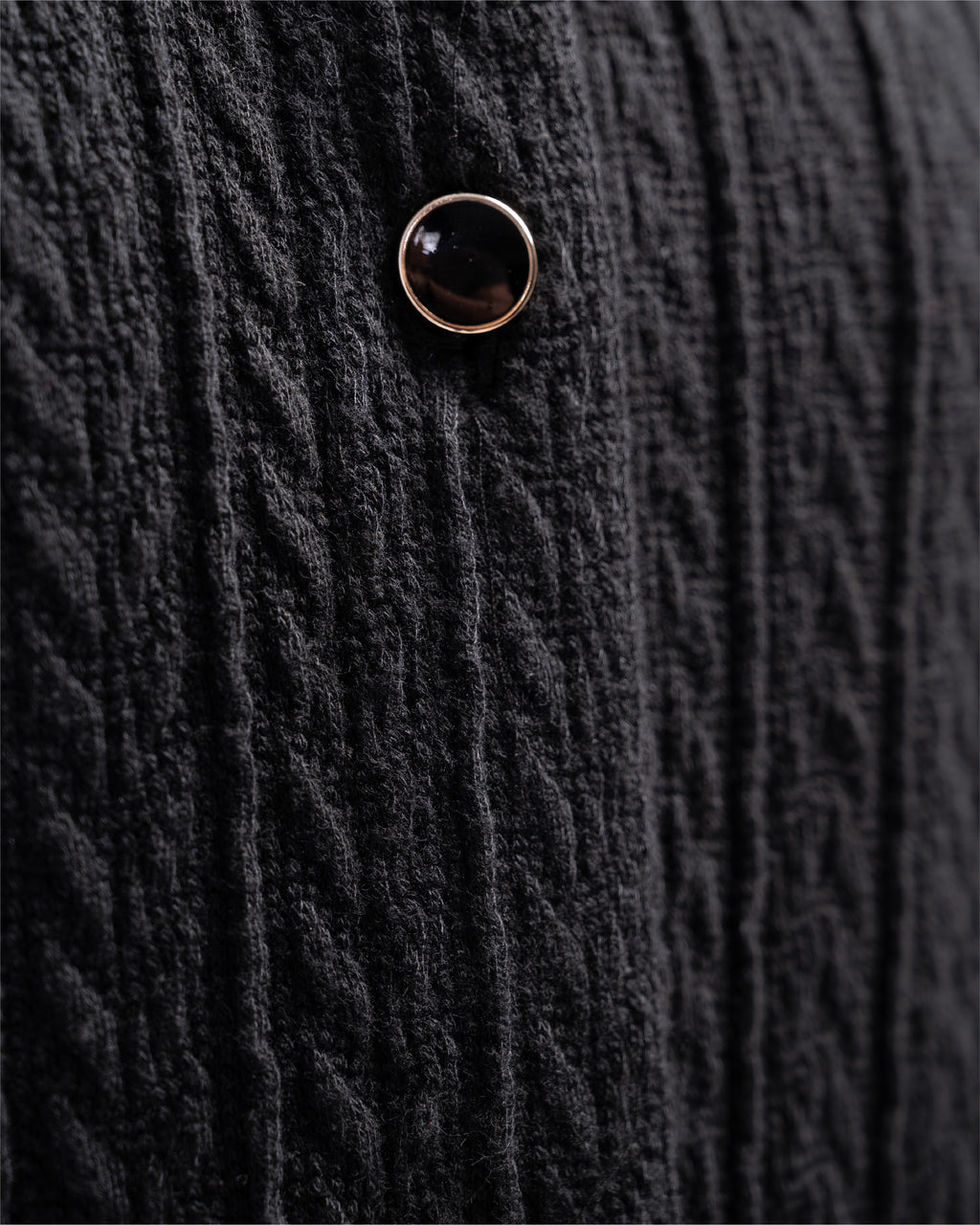 Close-up of a textured black fabric with a button detail