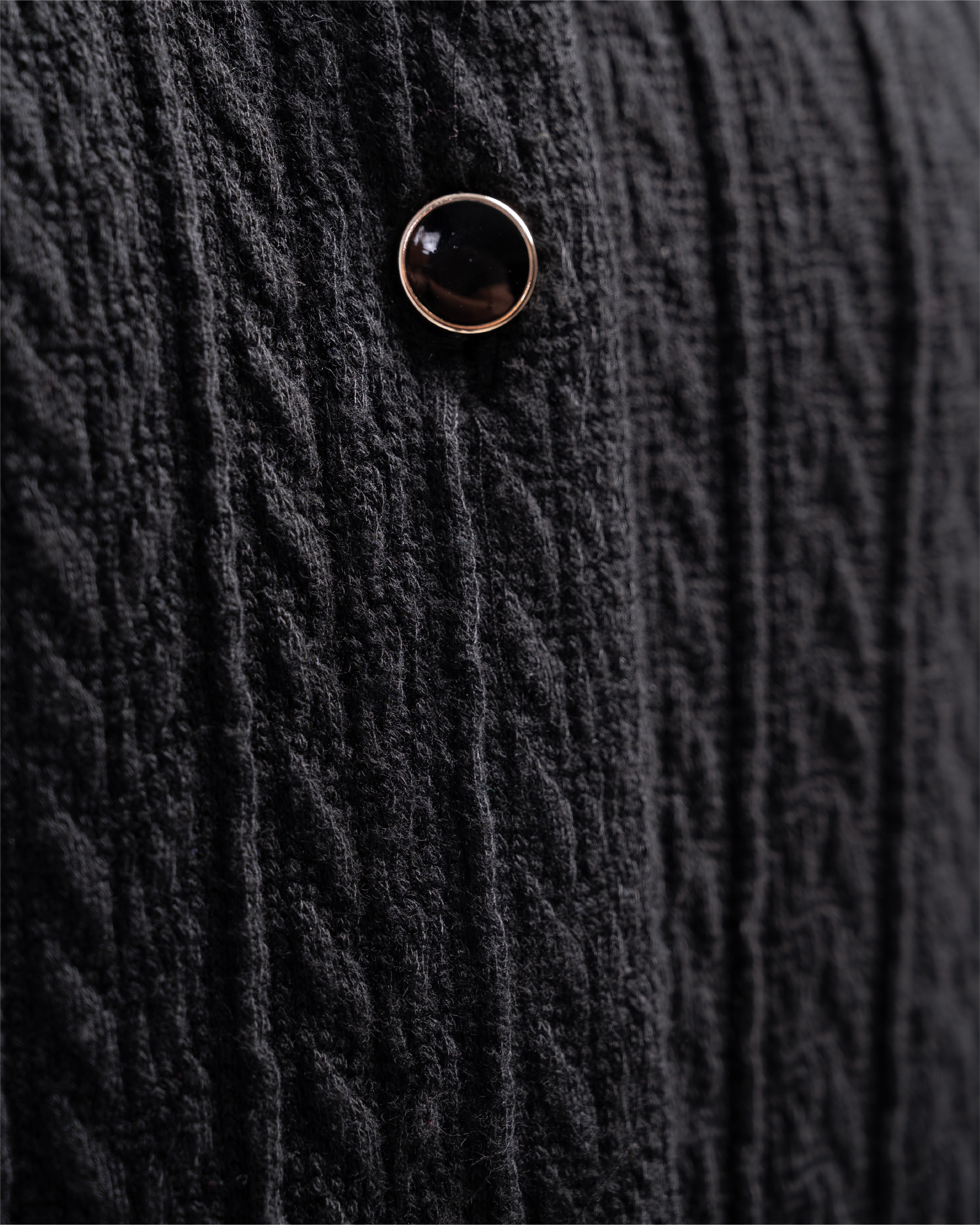 Close-up of a textured black fabric with a button detail