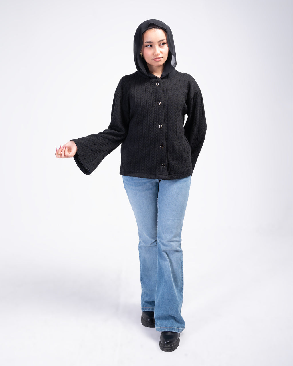 Person wearing a black cardigan and light blue jeans on a white background