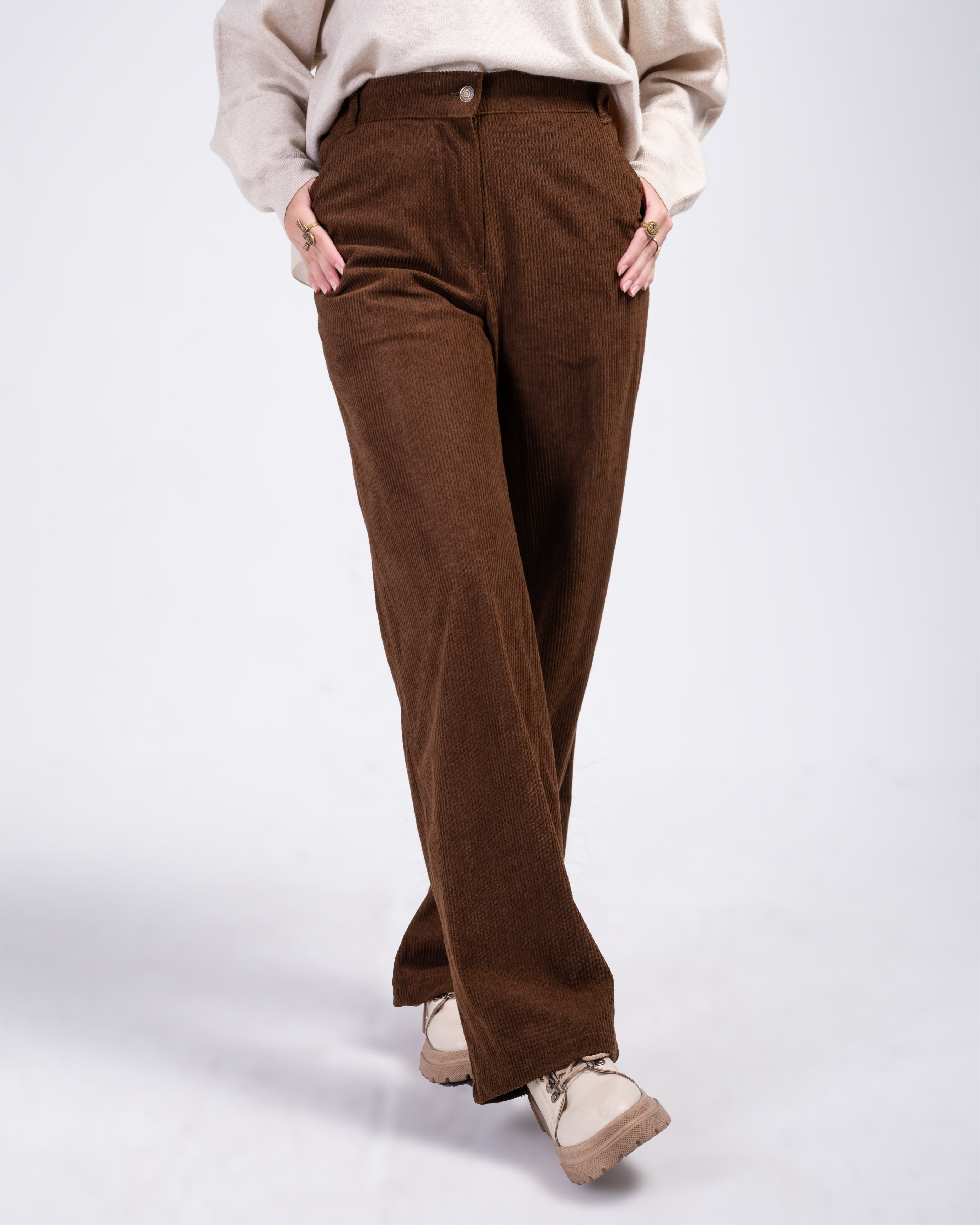 Brown corduroy pants worn by a person on a white background