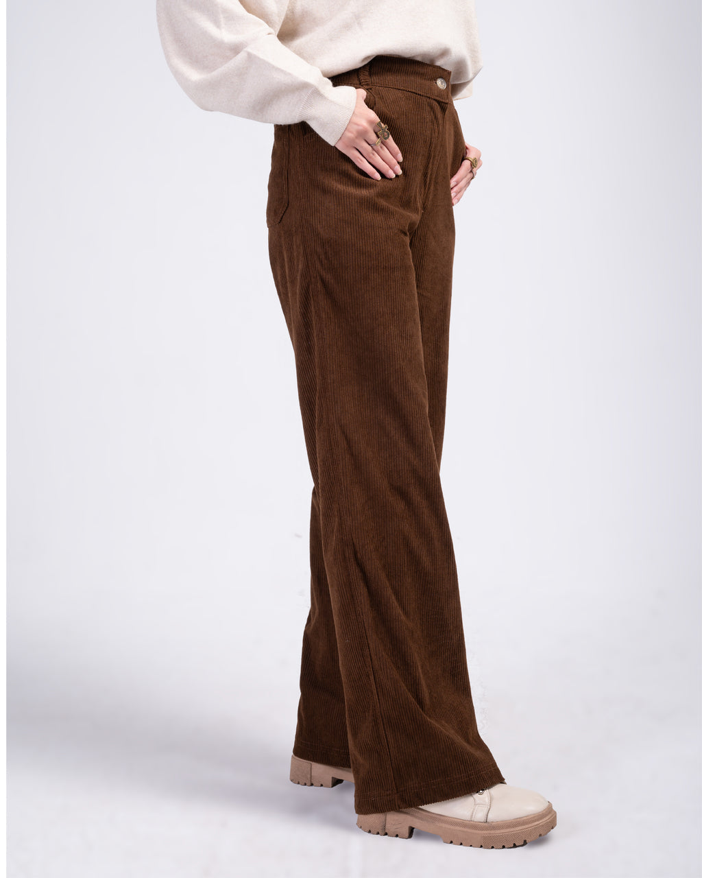 Brown corduroy pants worn by a person on a white background