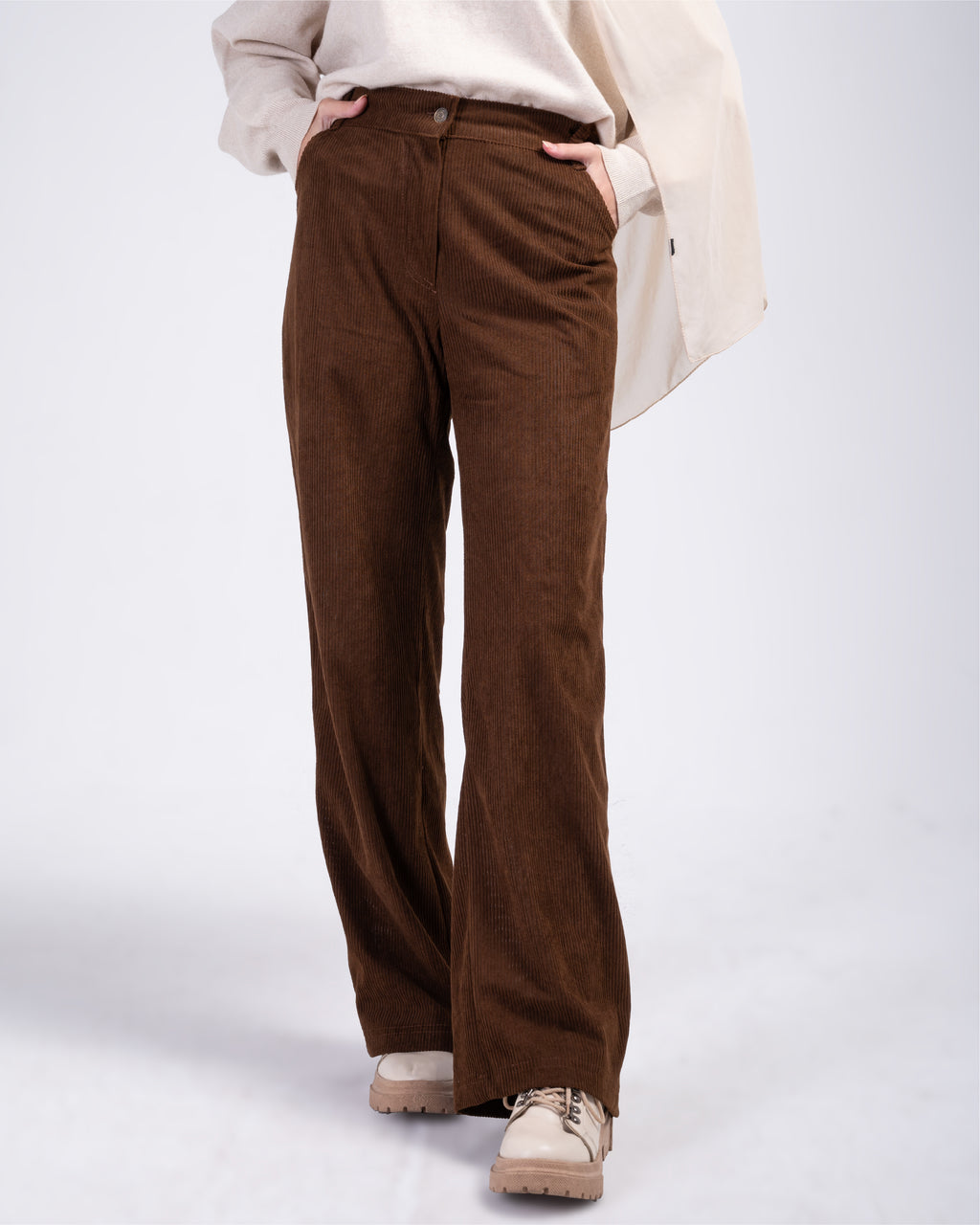 Brown corduroy pants worn by a person on a white background