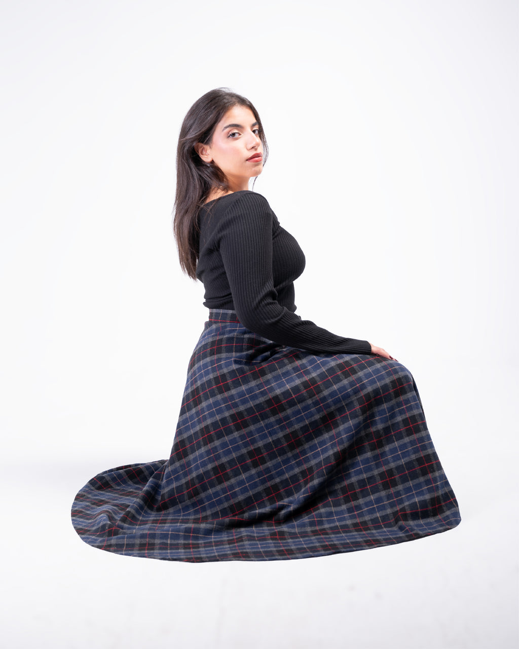 Woman wearing a black top and plaid skirt on a white background